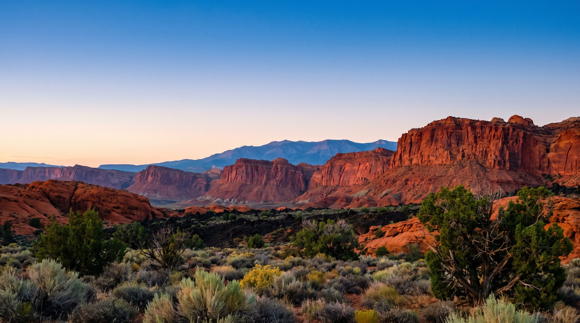 Desert-modern backyard beneath red rock cliffs at dusk